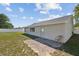 This backyard features grass, a partial brick patio and a chair next to the house with white trim and a fence at 11192 Archer Ave, Spring Hill, FL 34608