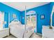 Bright bedroom features bold blue walls, a window letting in natural light, and a four poster bed with ornate white headboard at 11192 Archer Ave, Spring Hill, FL 34608