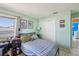 This bedroom has light blue walls, neutral tile flooring, and a comfortable bed with adjacent desk area at 11192 Archer Ave, Spring Hill, FL 34608