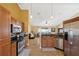 Kitchen area featuring stainless steel appliances, wooden cabinetry, and seamless access to the living room at 11192 Archer Ave, Spring Hill, FL 34608