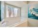 Light bathroom featuring soaking tub, window, and coastal-inspired artwork at 11291 Countrywood Ct, Spring Hill, FL 34609