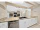 Modern kitchen flows into living area, featuring stainless appliances, granite counters, and white cabinetry at 11291 Countrywood Ct, Spring Hill, FL 34609