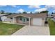 A one-story home with a brick exterior, attached garage, paved driveway, and well-manicured lawn at 12637 2Nd Isle, Hudson, FL 34667