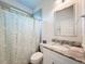 Bathroom featuring a floral shower curtain, framed mirror, and granite vanity top at 13349 Niti Dr, Hudson, FL 34669