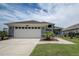 Inviting single-Gathering home featuring a spacious two-car garage, blue-grey facade and lush green lawn at 14011 Shoal Dr, Hudson, FL 34667