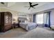 Serene main bedroom featuring a tray ceiling, ceiling fan, large window, and accent seating area at 14011 Shoal Dr, Hudson, FL 34667