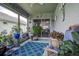 Bright, plant-filled sun room with cozy furniture and a charming blue patterned rug at 14011 Shoal Dr, Hudson, FL 34667