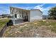 Exterior view of a white home featuring a covered patio with wooden steps and landscaped surroundings at 16037 Brookridge Blvd, Brooksville, FL 34613