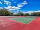 Exterior shot of well-maintained tennis courts with a vibrant red and green color scheme at 16037 Brookridge Blvd, Brooksville, FL 34613