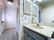 This bathroom features a vanity with a white countertop, wallpaper, and tiled laminate floors at 2139 Sea Pines Ct, Spring Hill, FL 34606