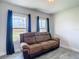 Comfortable living room with a brown leather couch and views of the outside from the two windows at 277 Hampshire Ave, Spring Hill, FL 34606
