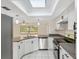 Bright kitchen features white cabinetry, modern appliances, and granite countertops, enhanced by a skylight at 3427 Charmwood Ave, Spring Hill, FL 34609