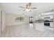 Bright living space boasts white tile floors, ceiling fans, and an adjacent kitchen with modern appliances at 3427 Charmwood Ave, Spring Hill, FL 34609