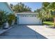 Spacious two-car garage featuring light blue exterior, a side entrance, and a wide concrete driveway at 3609 Montclair Dr, New Port Richey, FL 34655