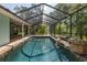 An enclosed pool with a rock waterfall sits in a screened enclosure surrounded by greenery at 3609 Montclair Dr, New Port Richey, FL 34655