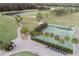 Scenic aerial view of golf course, lake, tennis court, and parking area with golf carts at 3627 Muirfield Ct # 3627, New Port Richey, FL 34655
