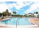 A beautiful pool with brick trim is surrounded by palm trees and lounge chairs under sunny skies at 3627 Muirfield Ct # 3627, New Port Richey, FL 34655