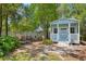 Charming blue shed with a porch, surrounded by lush landscaping and seating area at 4009 Clear Spring Rd, Brooksville, FL 34604