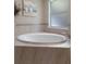Bright bathroom featuring a large soaking tub with tile surround, a painting, and a frosted window at 4009 Clear Spring Rd, Brooksville, FL 34604