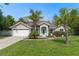 Charming single-story home featuring a two-car garage, beautifully landscaped yard, and a quaint, welcoming entrance with a teal door at 4009 Clear Spring Rd, Brooksville, FL 34604