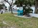 A private beach club entrance with manicured grass, palm trees, and a turquoise chair near the sign at 4726 Marine Pkwy # 104, New Port Richey, FL 34652