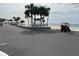 A beach parking area features a golf cart, covered picnic tables, calm ocean, and swaying palm trees at 4726 Marine Pkwy # 104, New Port Richey, FL 34652