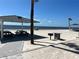 An open beach with fine sand, picnic tables under a covered pavilion, grill, and the ocean in the background at 4726 Marine Pkwy # 104, New Port Richey, FL 34652
