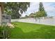 Large backyard featuring green grass, a white fence, and a screened-in pool, providing ample space and privacy at 4923 Fort Peck Rd, New Port Richey, FL 34655