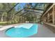 A serene private swimming pool surrounded by a screened enclosure and lush greenery at 5363 Utopia Pl, Brooksville, FL 34601
