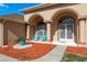 Inviting front porch with stylish columns, tiled floor, seating, and beautiful landscaping at 5423 Abagail Dr, Spring Hill, FL 34608