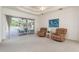 Bright and airy living room featuring plush armchairs, neutral carpet, and access to the screened pool area at 5423 Abagail Dr, Spring Hill, FL 34608