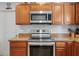 Features the stove, microwave, granite countertops, wooden cabinets and tiled backsplash at 6315 Shane Ln, New Port Richey, FL 34653