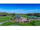 Aerial view of golf carts parked near clubhouse, green lawns and mature trees on a sunny day at 7392 Willow Brook Dr, Spring Hill, FL 34606