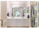 Bright bathroom featuring double sinks, large mirror, white cabinets, and a shower with a floral curtain at 7392 Willow Brook Dr, Spring Hill, FL 34606