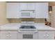 Close-up of a kitchen featuring white cabinets, countertops, and a smooth top range oven at 7392 Willow Brook Dr, Spring Hill, FL 34606