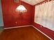 Dining room featuring hardwood floor, chandelier, and a red accent wall at 7421 Fairfax Dr, Port Richey, FL 34668