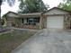 Charming home with a rock facade, attached garage, and inviting front porch with chairs and table at 7421 Fairfax Dr, Port Richey, FL 34668
