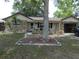 Inviting home with rock facade, featuring a well-kept yard with a mature tree and decorative landscaping at 7421 Fairfax Dr, Port Richey, FL 34668