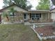 Home featuring a rock facade and a charming front porch with chairs and a small table at 7421 Fairfax Dr, Port Richey, FL 34668