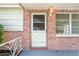 Close-up of a brick facade featuring a decorative front door and adjacent window with white trim at 7810 Chalafonte Dr, Port Richey, FL 34668