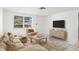 Staged living room with tile flooring, neutral furniture, a large window, and a modern TV console at 7810 Chalafonte Dr, Port Richey, FL 34668