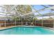 Clear pool with chairs and a wooden fence, enclosed in a screened cage at 7810 Chalafonte Dr, Port Richey, FL 34668