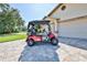 Eye-level shot of a red golf cart parked in the driveway of a beige home with a three car garage at 8132 Summersong Ct, Spring Hill, FL 34606
