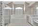 Bathroom featuring large tub beneath arched window with a separate glass shower at 8228 Coral Creek Loop, Hudson, FL 34667