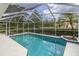 A screened-in pool offers a refreshing escape with lush landscaping and a beautiful sky above at 8228 Coral Creek Loop, Hudson, FL 34667