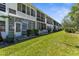 Exterior view showcasing the backyard with lush lawn and foliage, and the building's rear facade at 8405 112Th St # 103, Seminole, FL 33772