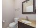 Powder room with a dark wood vanity, an oval sink, a mirror and a standard toilet at 8526 Hawbuck St, Trinity, FL 34655