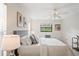 Cozy bedroom with a ceiling fan, white bedding, and modern artwork at 8700 Wind Mill Dr, New Port Richey, FL 34655