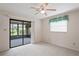 Bright bedroom featuring neutral carpet, a ceiling fan, and a sliding door to a screened-in porch at 8700 Wind Mill Dr, New Port Richey, FL 34655