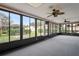 Enclosed lanai featuring floor-to-ceiling windows offering backyard views and ceiling fans at 8700 Wind Mill Dr, New Port Richey, FL 34655
